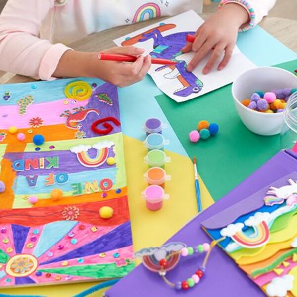 child coloring picture on table with crafts